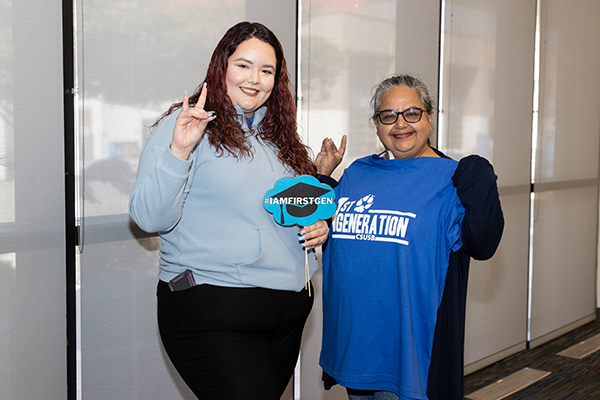 Two attendees hold up first-generation T-shirts