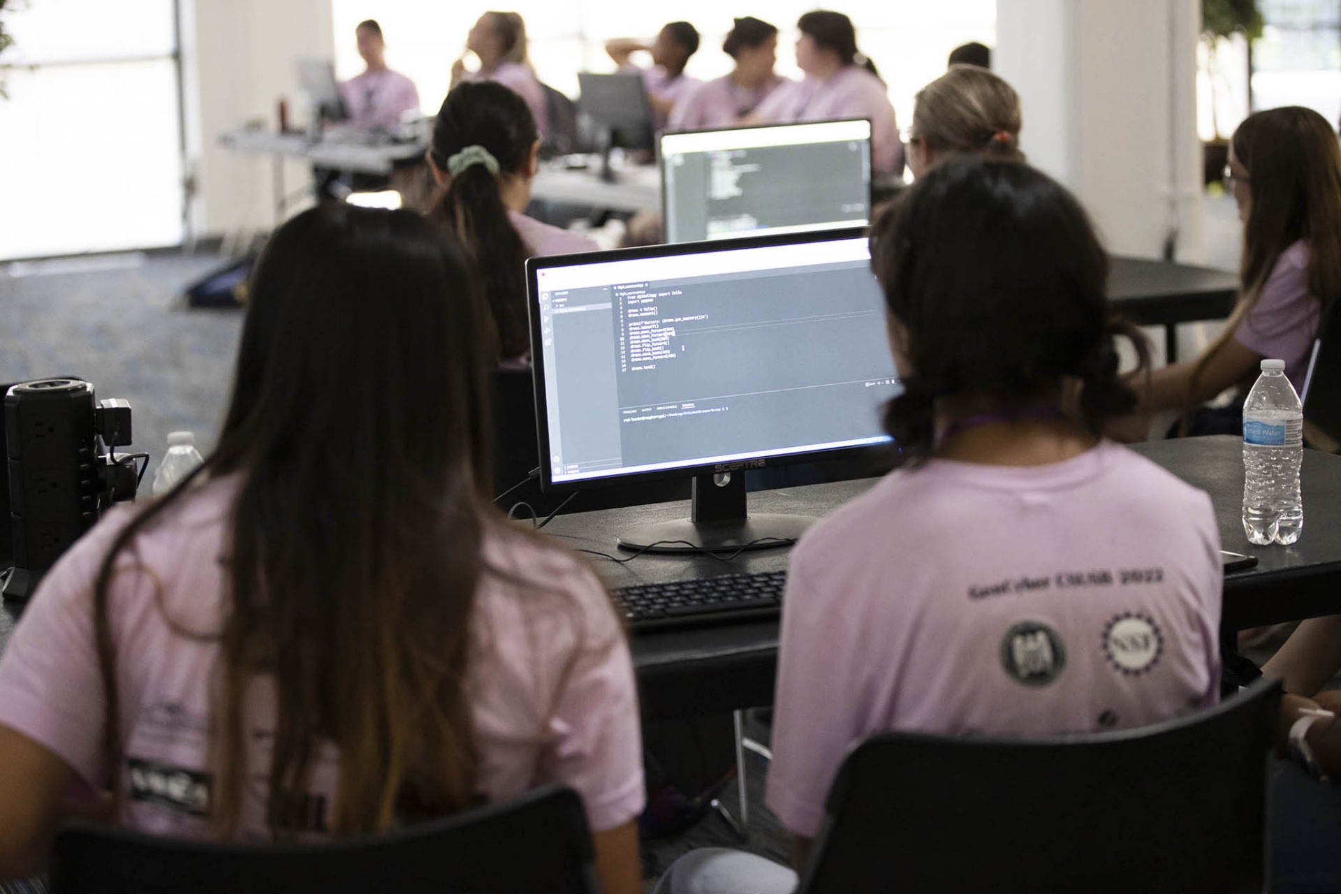 Two GenCyber campers monitor their work on their computers.