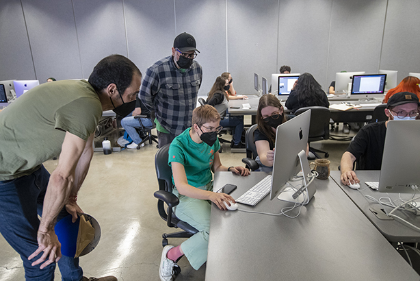 Standing, from left, are Daniel Ruanova, international artist and artist-in-residence, and Ed Gomez, CSUSB associate professor of art and design, look over a student’s work.