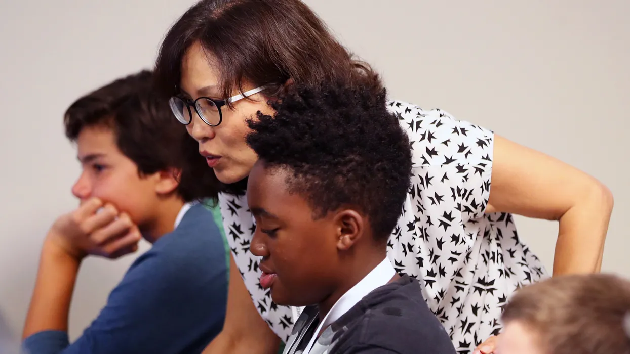 image of teacher helping students with computer