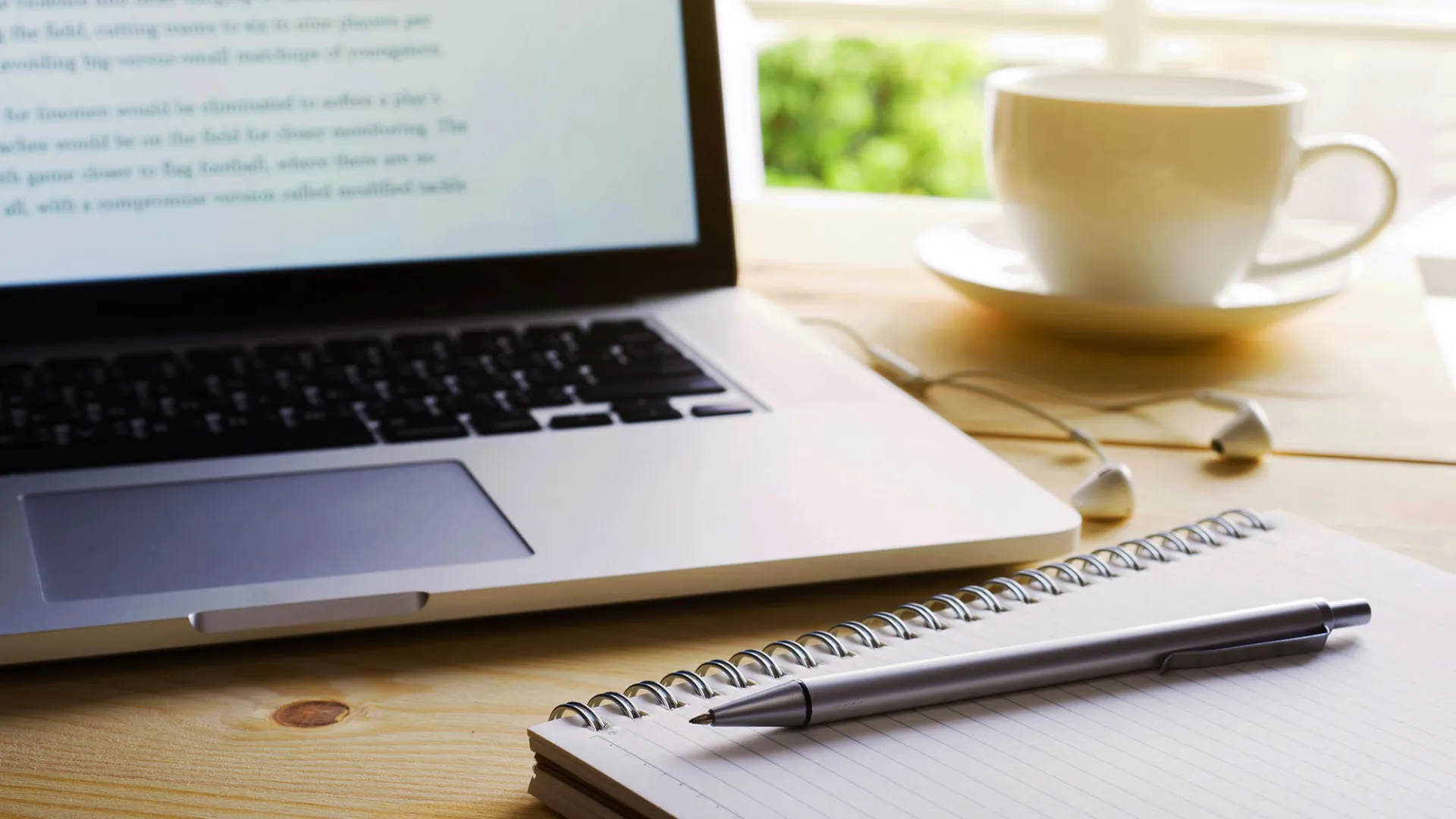 Photo of a laptop and a writing pad and pen.