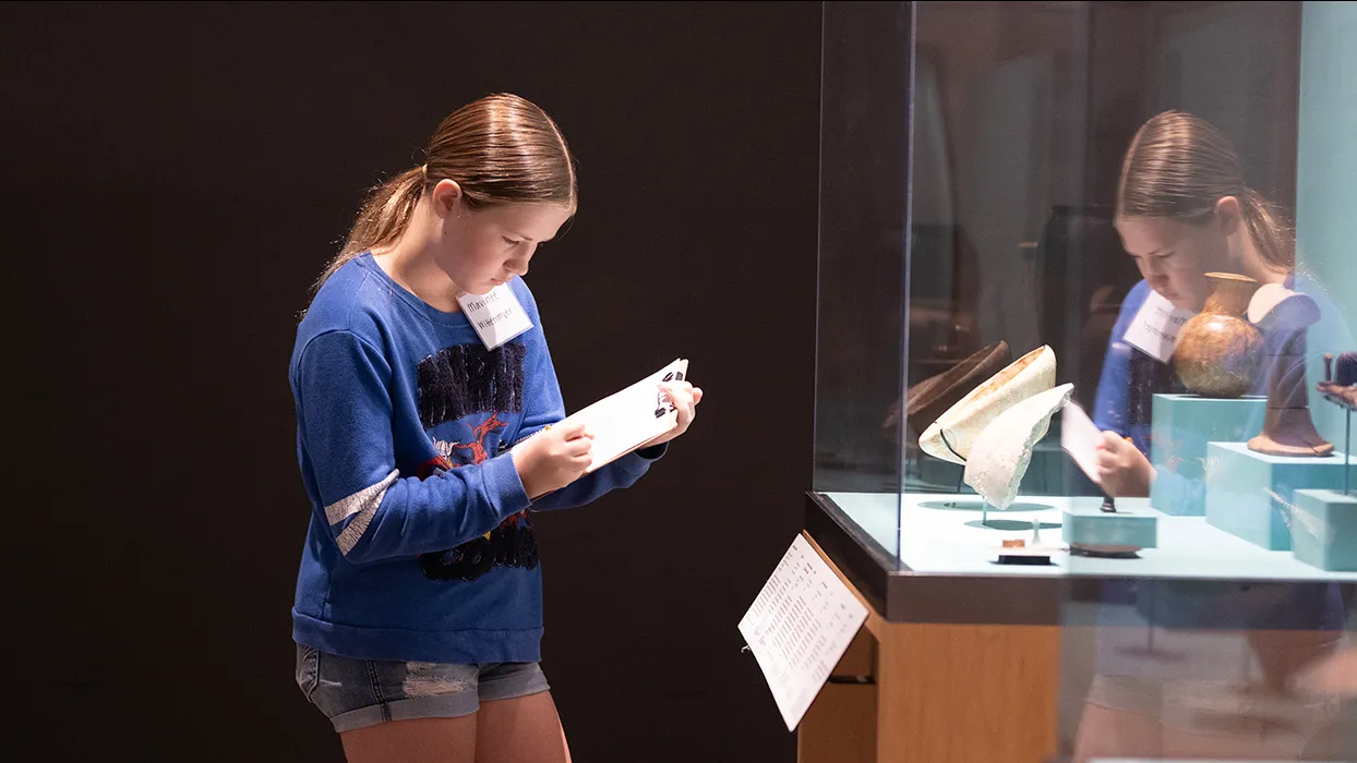 A participant of the Kids Discover Egypt Workshop examines an art exhibit at RAFFMA.