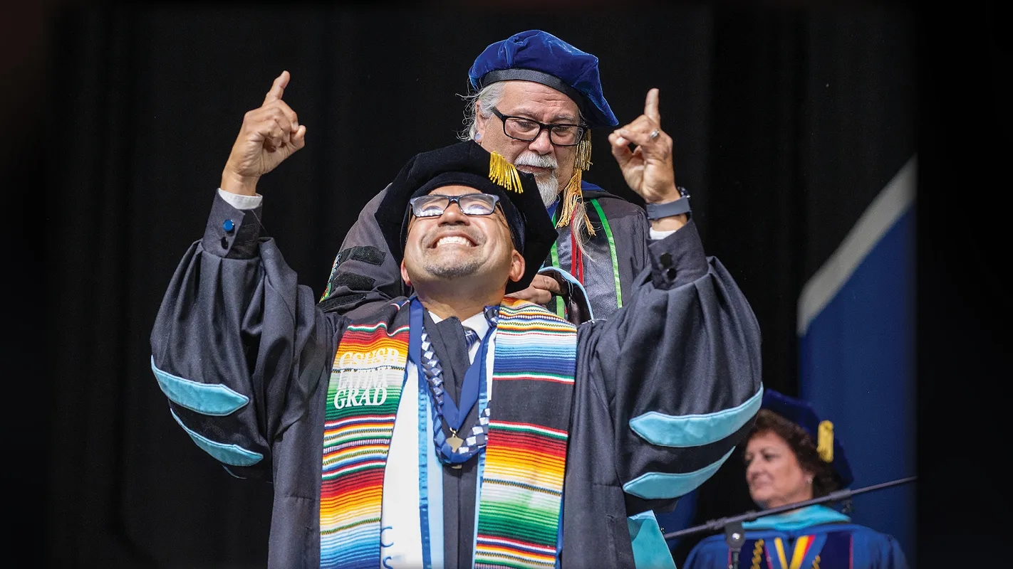 Juan Carlos Luna (front), is awarded his doctorate degree from Enrique Murillo Jr. director of Doctorate in Educational Leadership program in the James R. Watson & Judy Rodriguez Watson College of Education, during the May 2025 Commencement exercises.