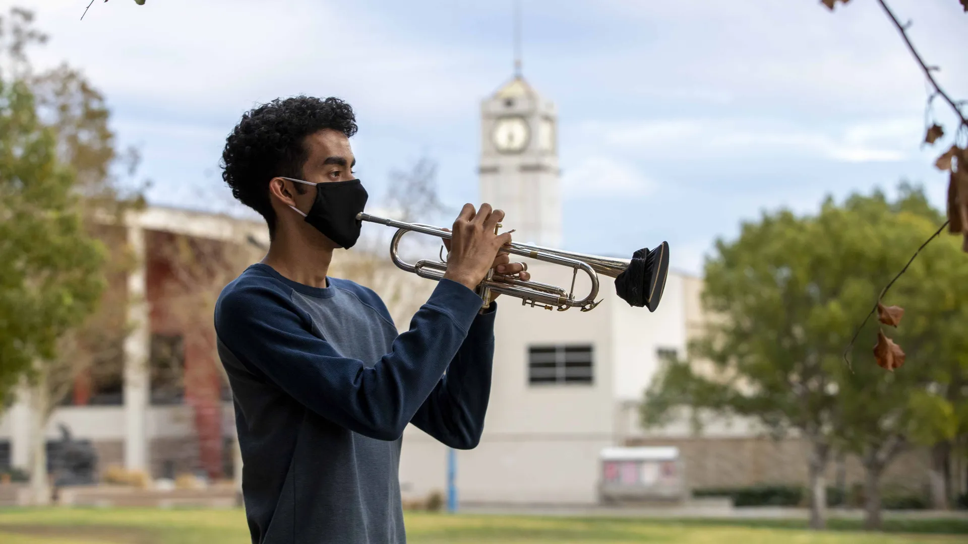 CSUSB student William Parada plays his trumpet outside. Through a series of approved hybrid classes and safety precautions, the music lives on. 