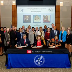 A group of people look on as HHS and CSU officials sign documents.
