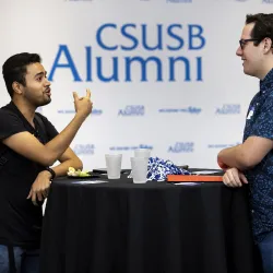 Two people talking at at table. CSUSB Alumni host Amazon Finance Panel session