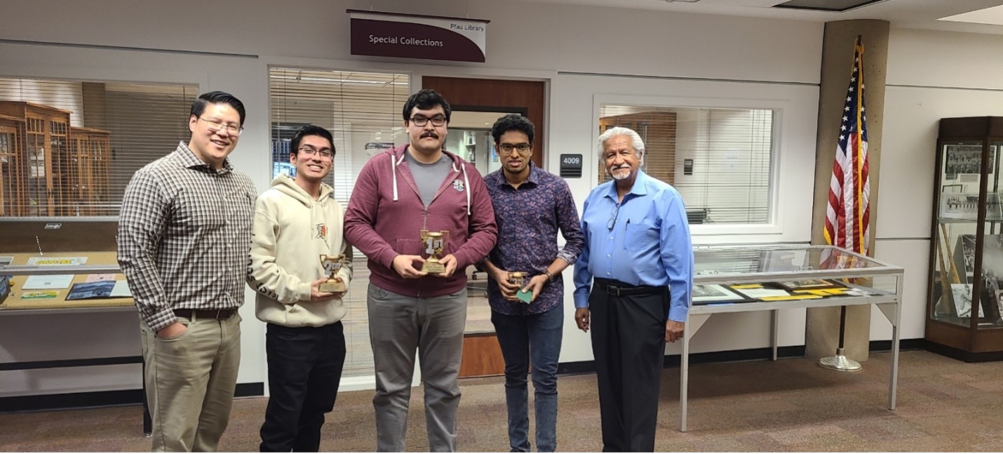 Chris Han (past-president of the Chess Club and current member of the newly formed Chess Kings (support group) is standing to the left of the winners.  Cesar Caballero, dean emeritus of the Pfau Library is standing to the right of the group.  He is the current lead for chess activities on campus