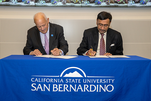 CSUSB President Tomás D. Morales (left) and Tomar Balvir, founder and chancellor of NIMS University, India, sign a Memorandum of Understanding (MOU) on Dec. 6, 2023.