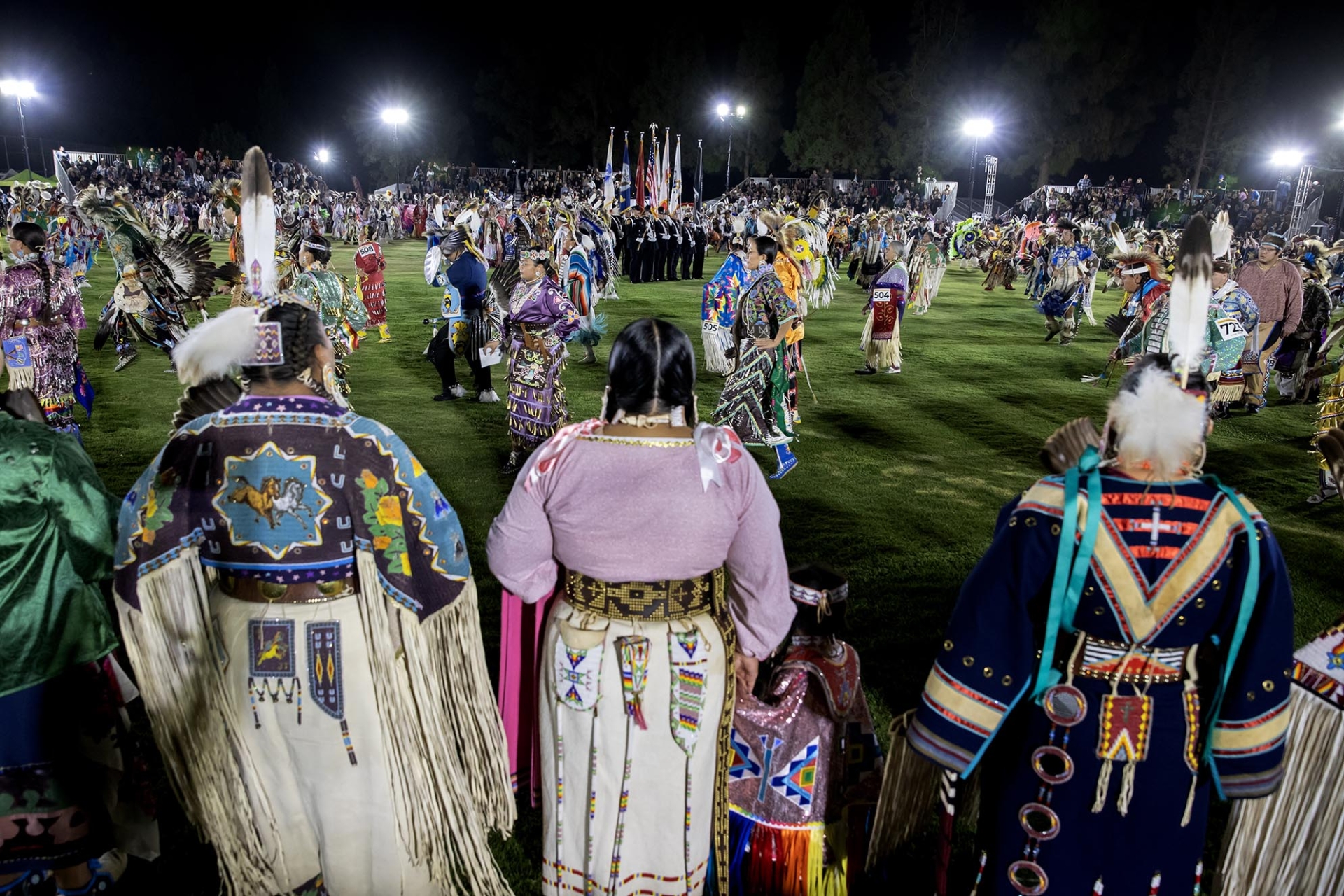 A crowd looks on as dancers make their way around the field during the 2024 San Manuel Pow Wow.