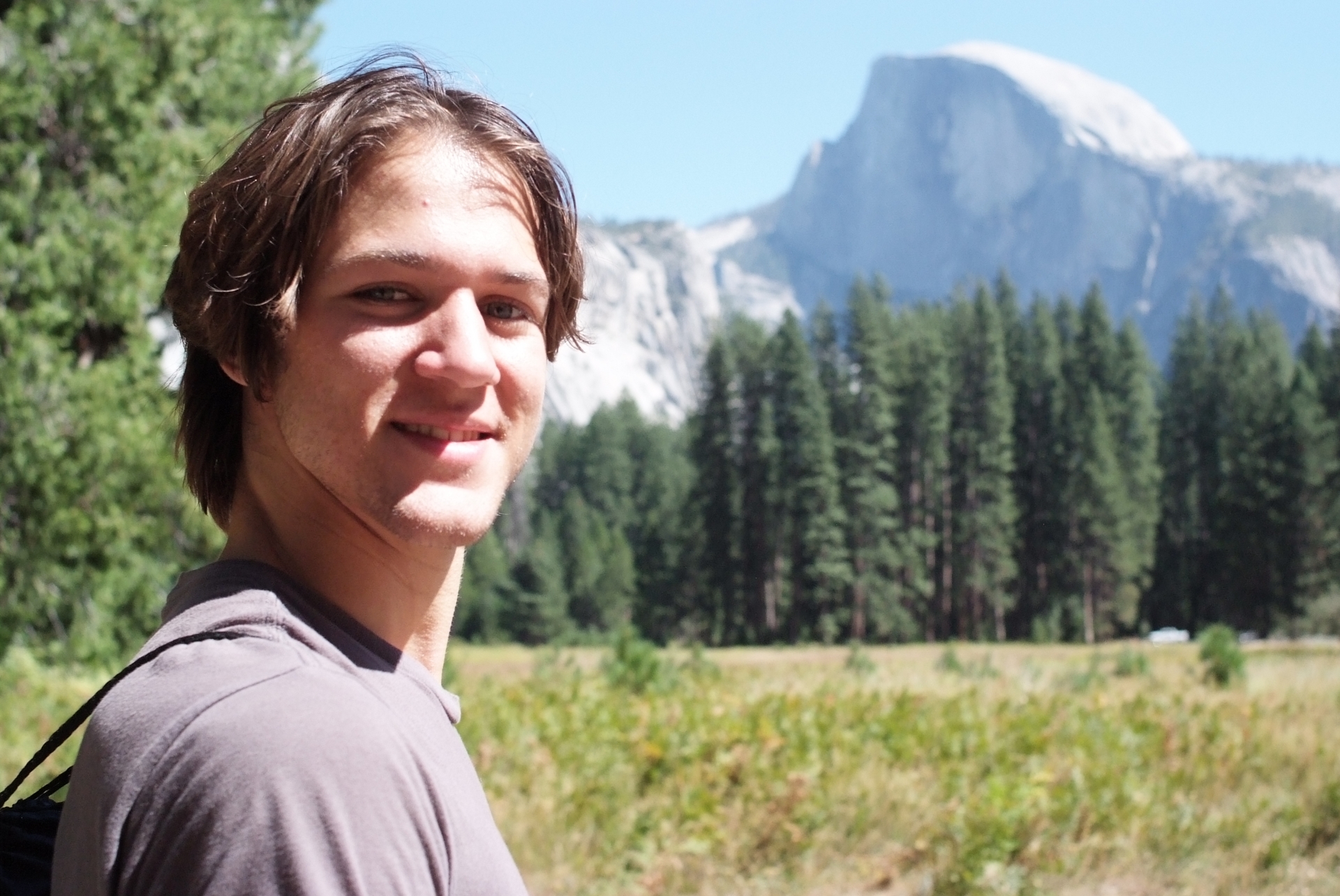 young man looking at half dome from meadow
