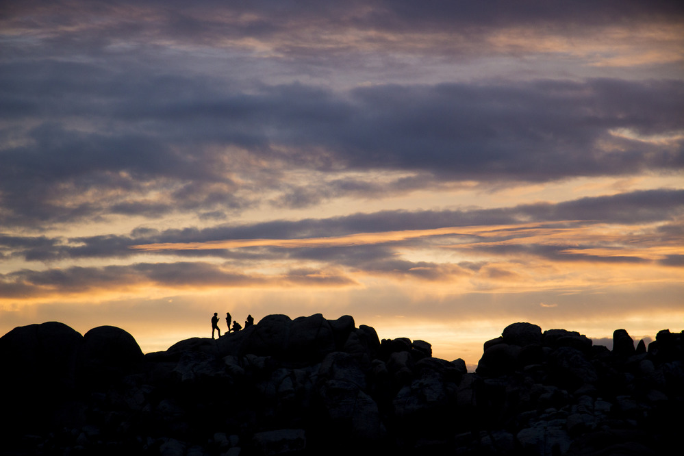 sunset behind rock ridge with hikers on it. 