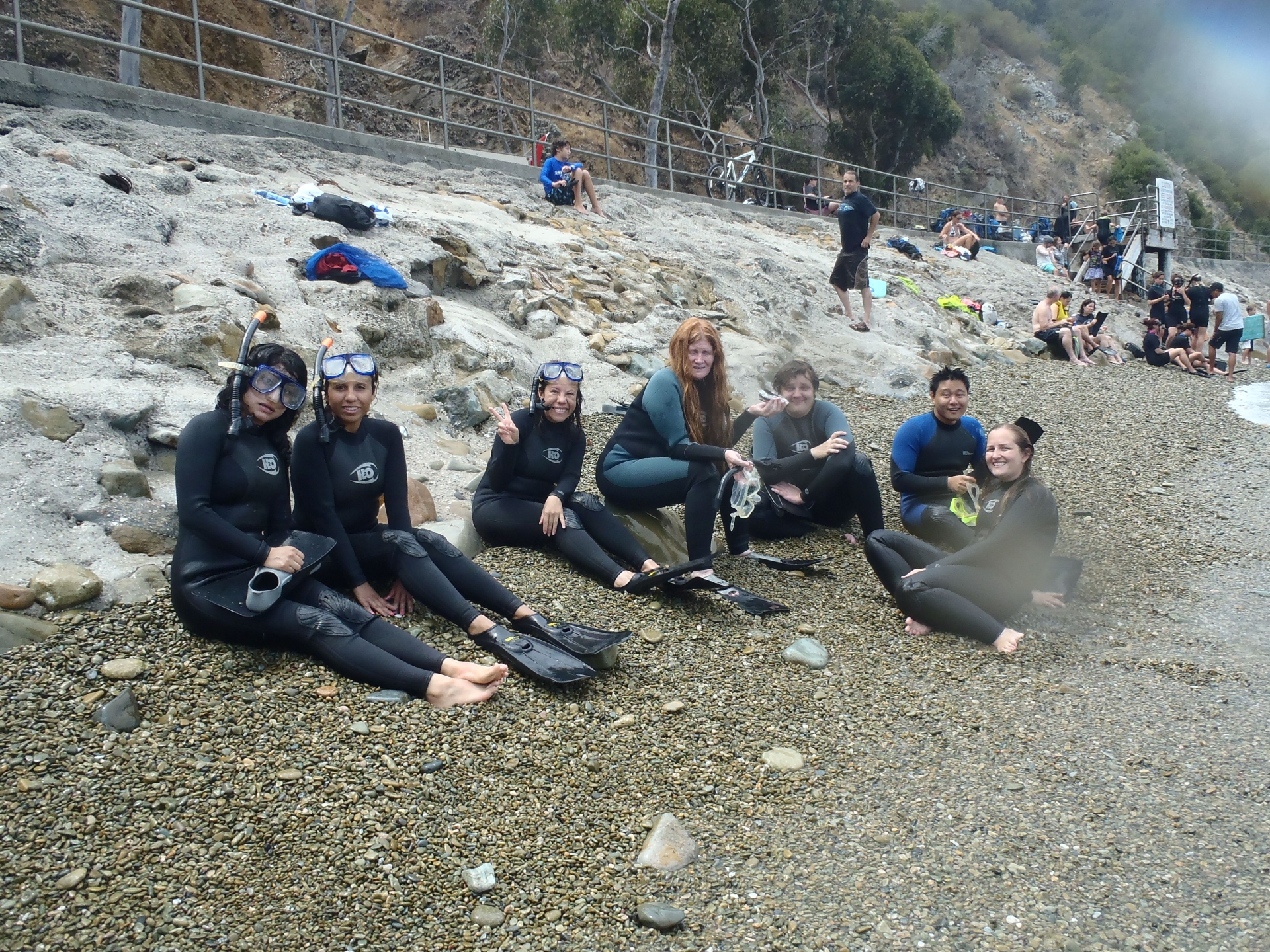 7 people in wetsuits on the beach after snorkeling 