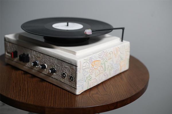 A close-up of hand-carved details on a ceramic record player, created by Katherine Yvonne Posada. This piece holds the intimate audio recording of the last conversation with the artist’s grandmother, preserved forever on vinyl.