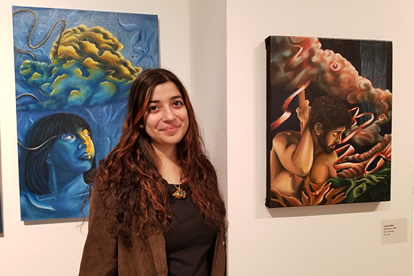 Loren Malul with her contemporary surrealist paintings at the second-year MFA exhibition. 