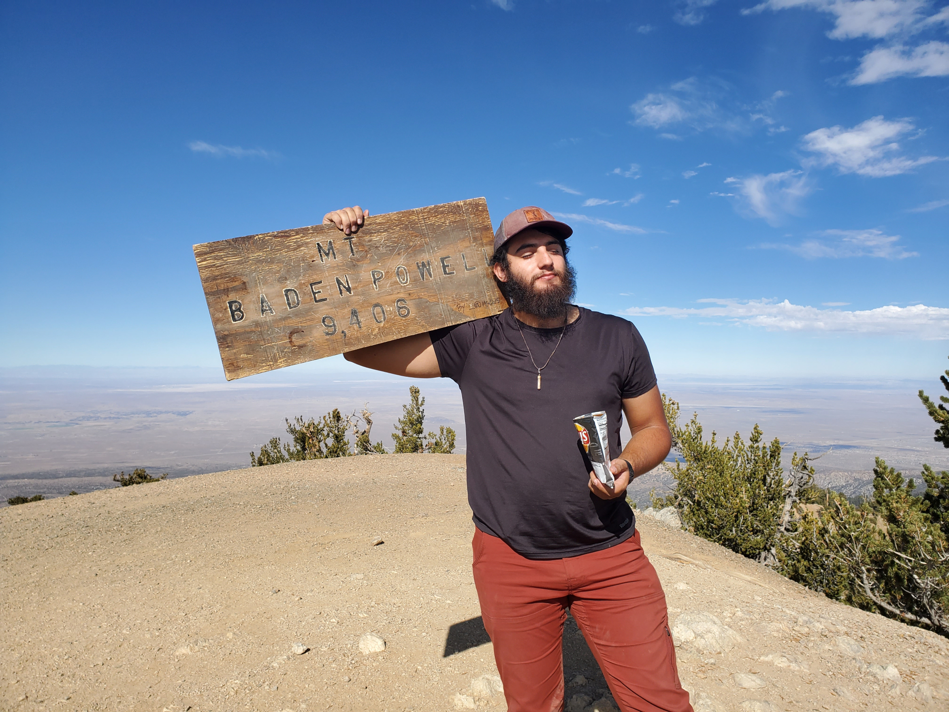 man holding sign Mt Baden-Powell 9,406 feet